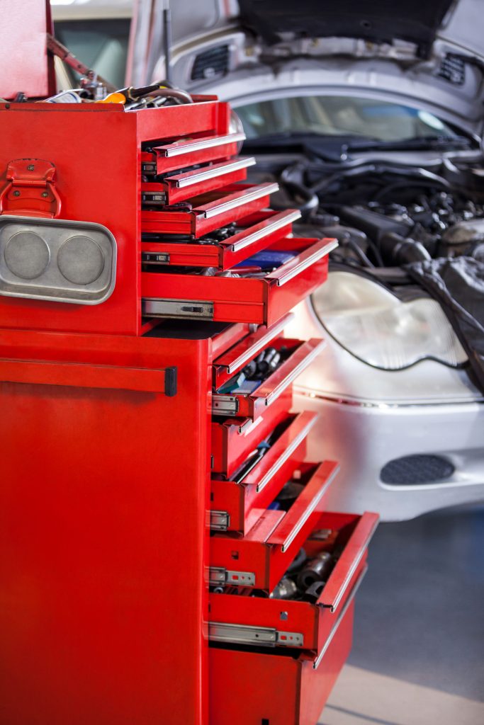 Autohuollon työkalut laatikossa. Mercedes-Benz auto huollettavana taustalla. Autohuolto